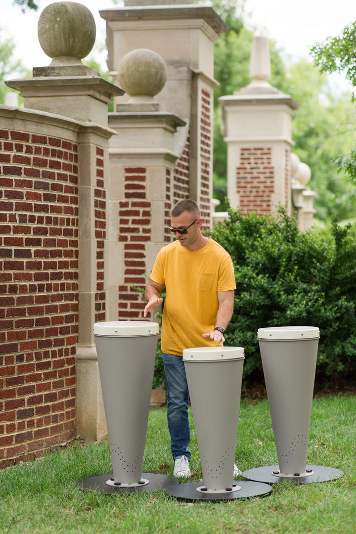 Man playing with a drum set at a campus