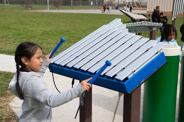 little girl playing xylophone at the park