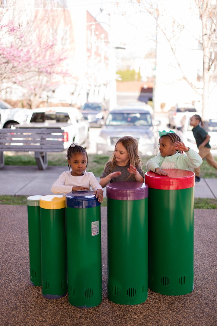 Young girls playing drums at the park