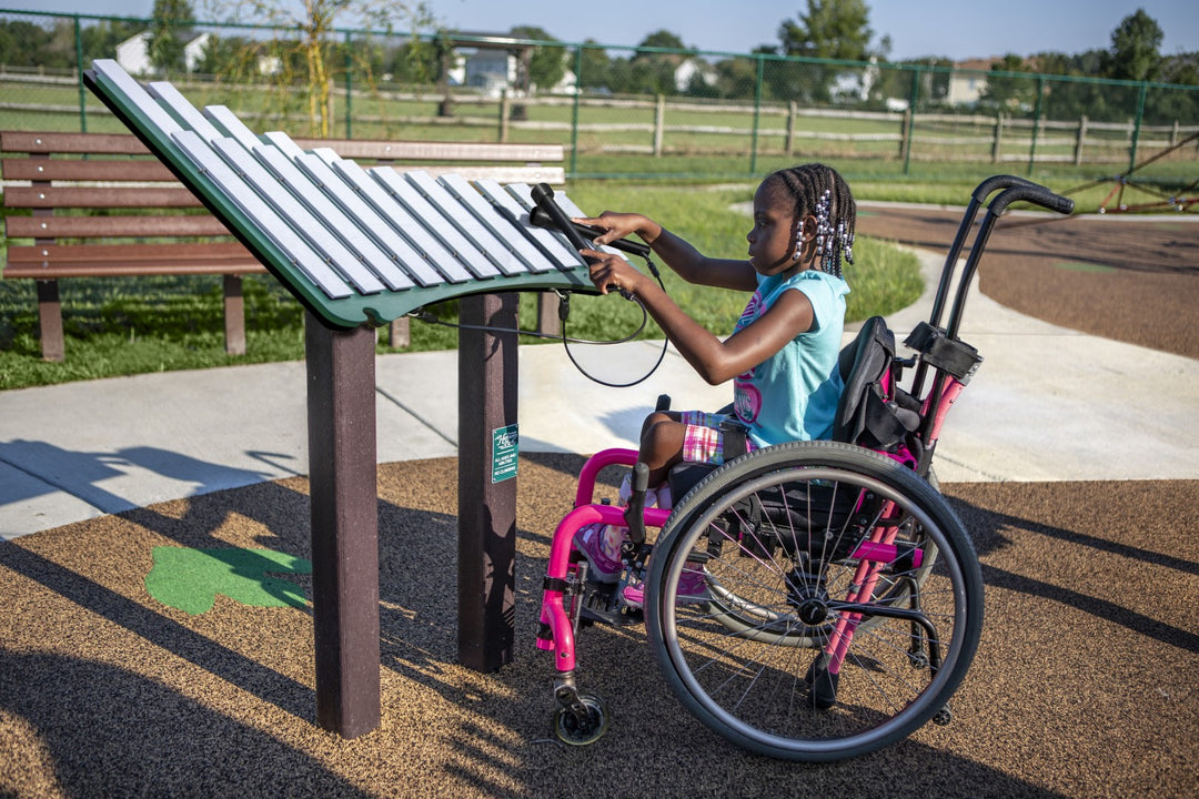 a young girl in a wheelchair playing with the merry instrument